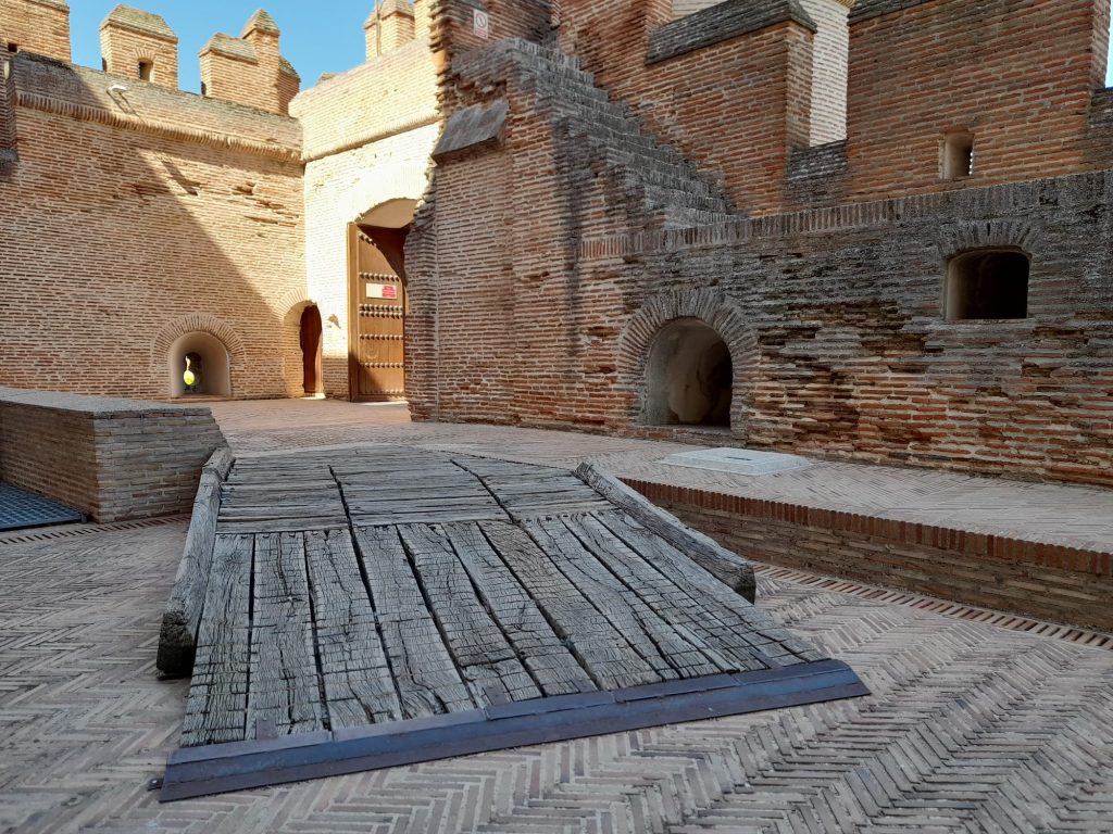 Exteriores de castillo con paredes de piedra y rampa de acceso de madera