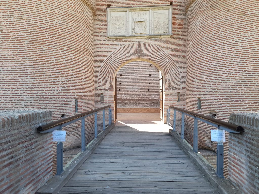 Entrada al castillo donde se puede ver pasarela de madera y arco de ladrillo