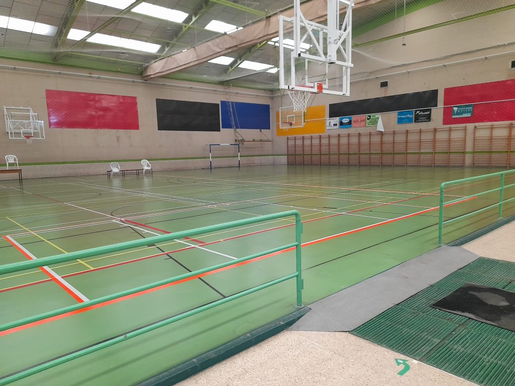 Interior de polideportivo donde se ve una canasta